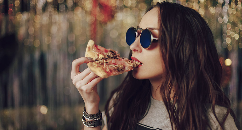 woman with sunglasses eating pizza