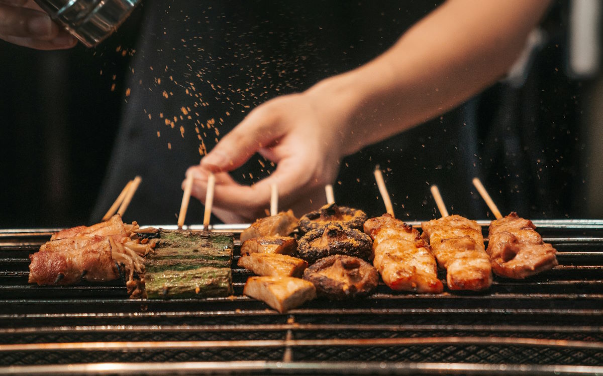 seasoning meat skewers on the BBQ